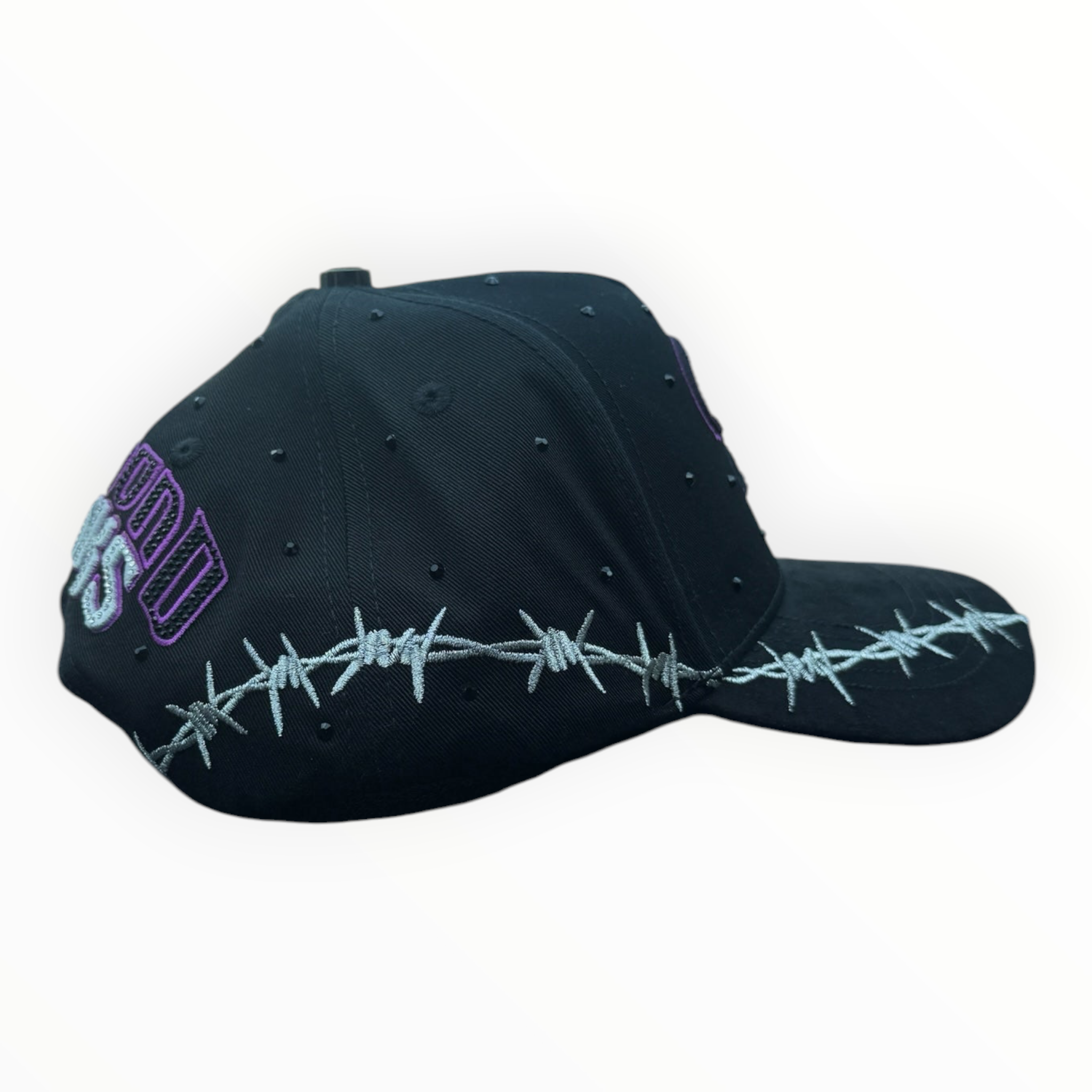 Hype Block black baseball cap with silver barbed wire embroidery, purple lettering, and stud details on a car dash