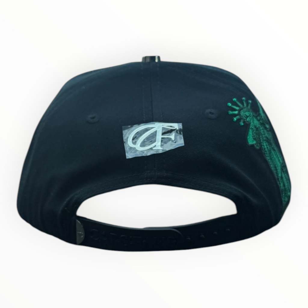 Hype Block black baseball cap with green Statue of Liberty embroidery on the side, resting on a car dashboard.