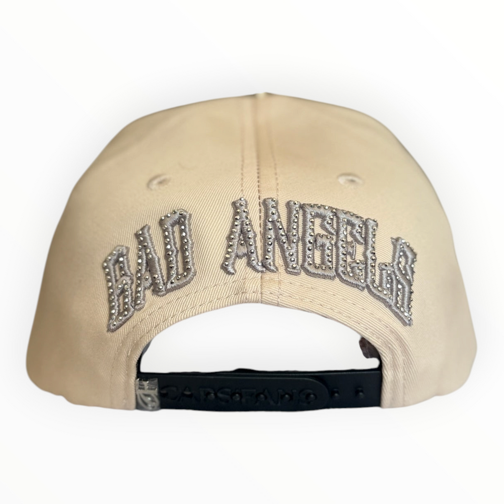 Hype Block cream snapback cap featuring BAD ANGELS text embroidered with sparkling rhinestones on the back panel.