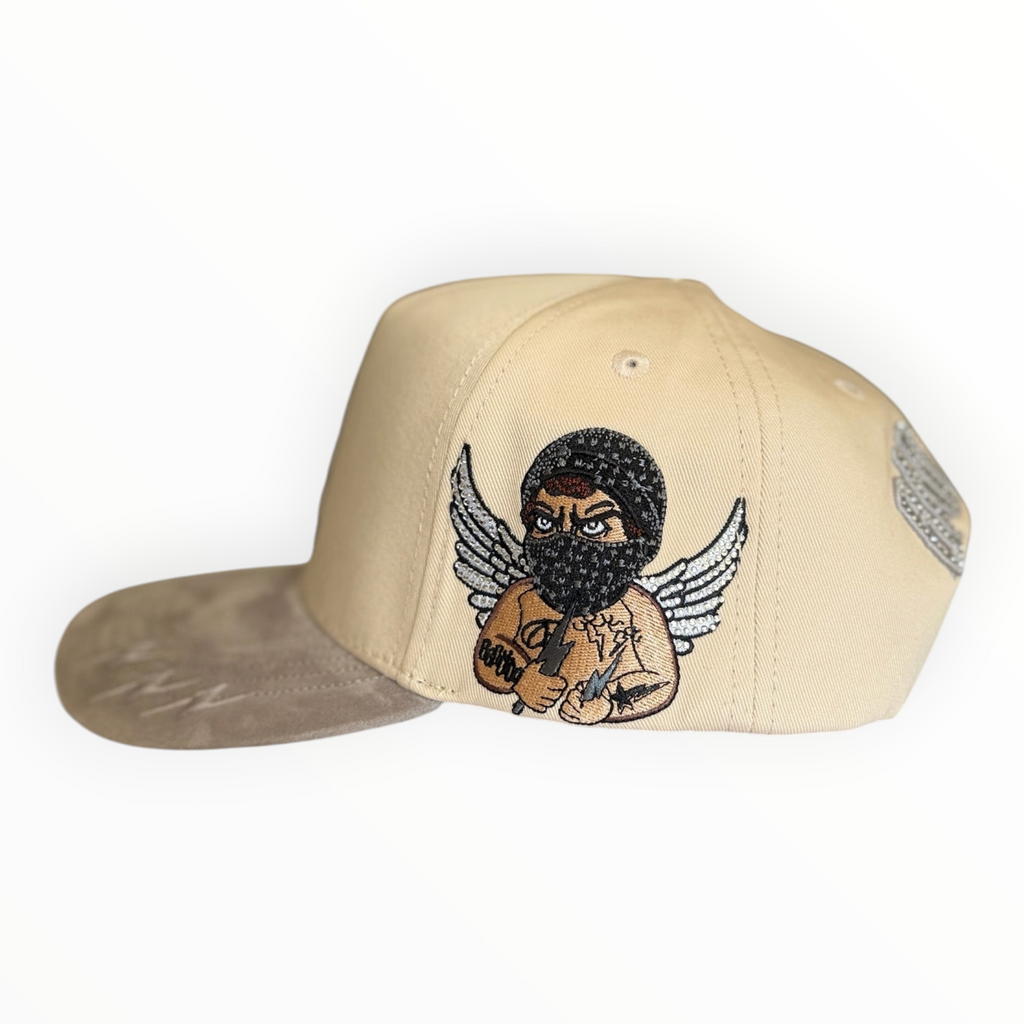 Hype Block cream snapback cap with taupe suede brim and detailed Bad Angel graphic embroidery on the side panel