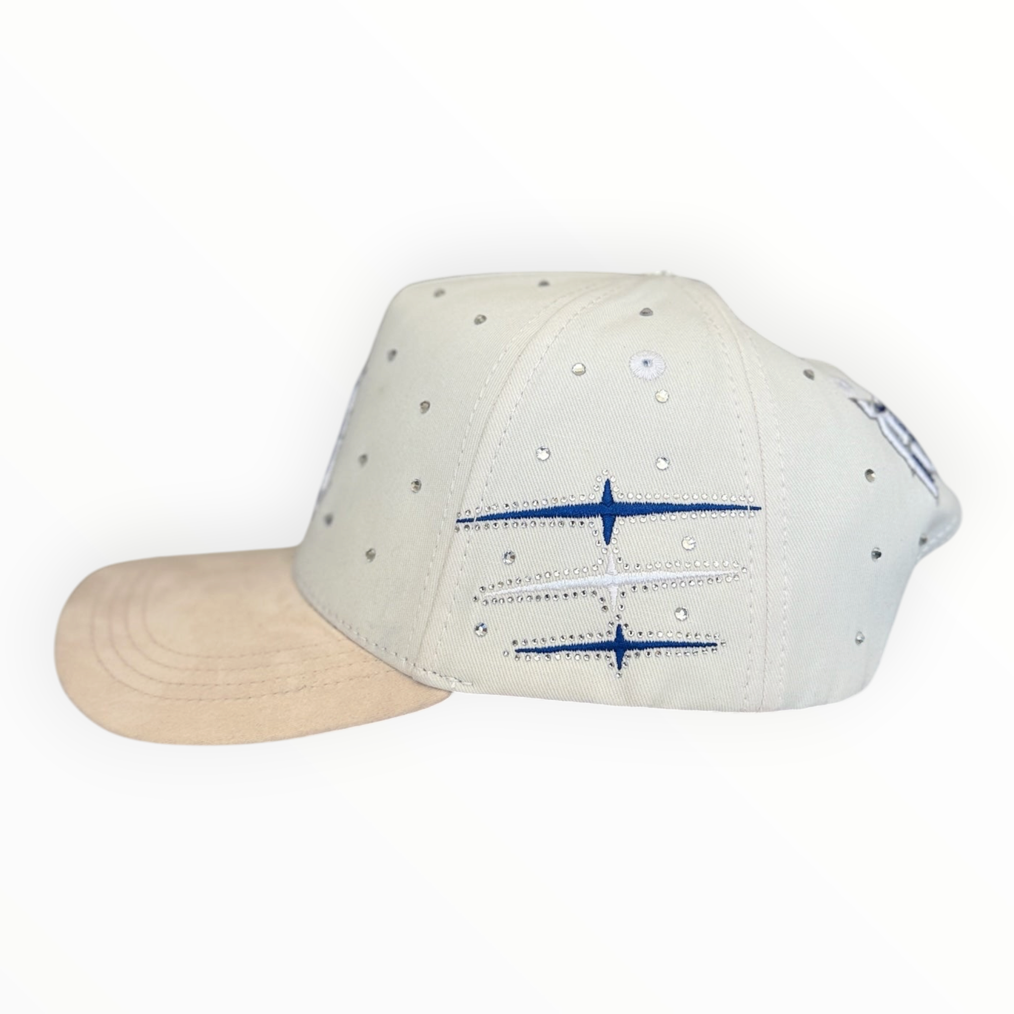 Hype Block white baseball cap with scattered rhinestones, beige suede brim, and blue embroidered side graphic detail.