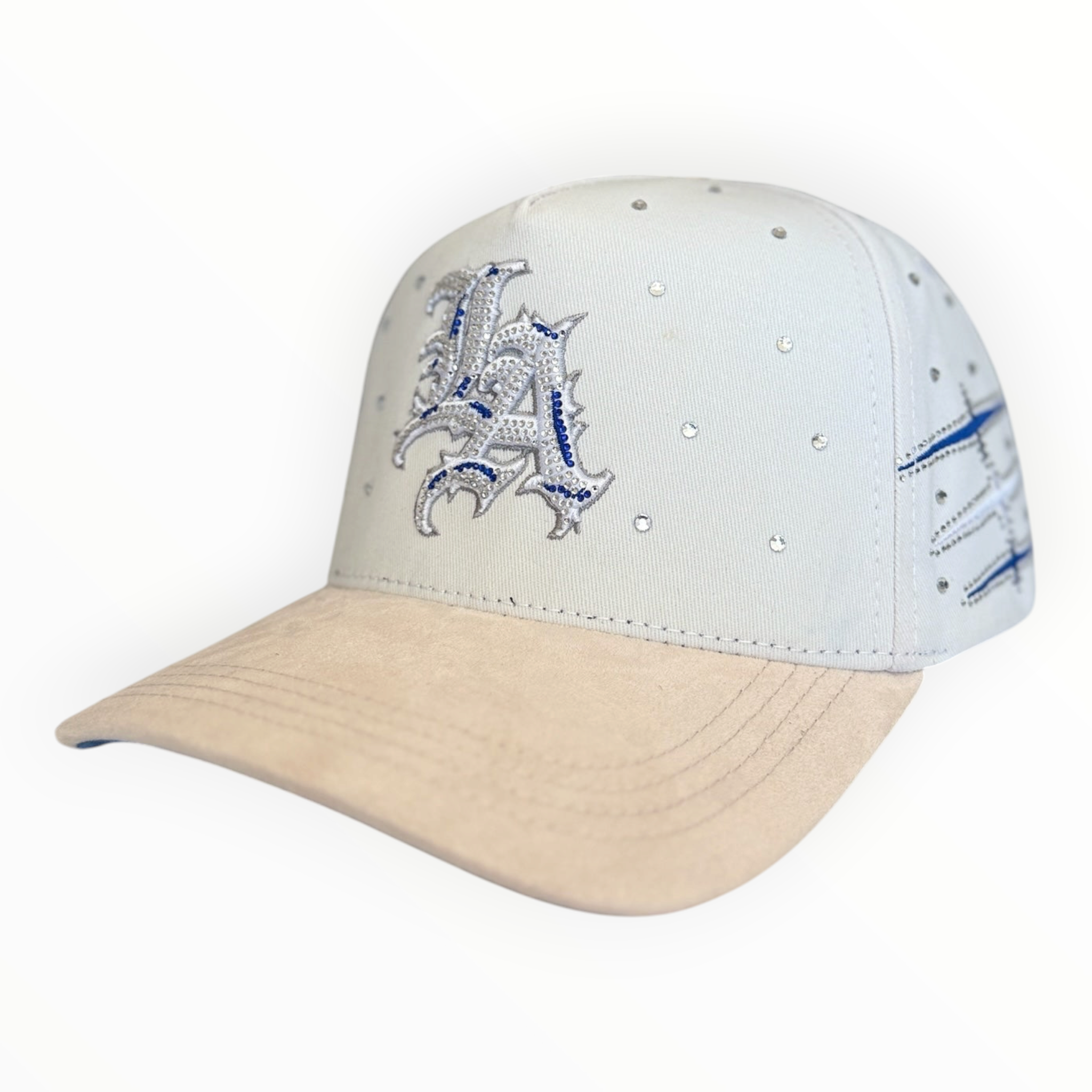 Hype Block white baseball cap with rhinestone LA logo, blue embroidery, and a beige suede-feel brim.
